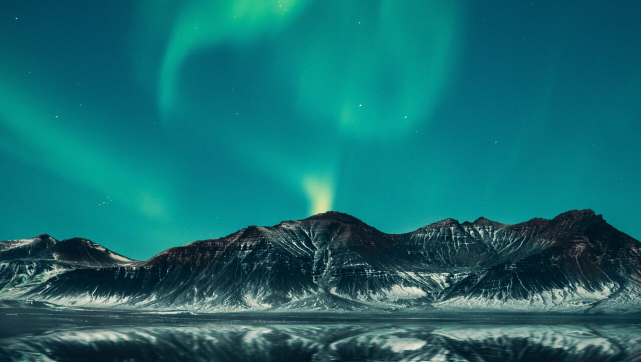 Scenic night view of Reykjavik, Iceland, illuminated by city lights amidst lush greenery, showcasing the captivating beauty of the Icelandic capital at night